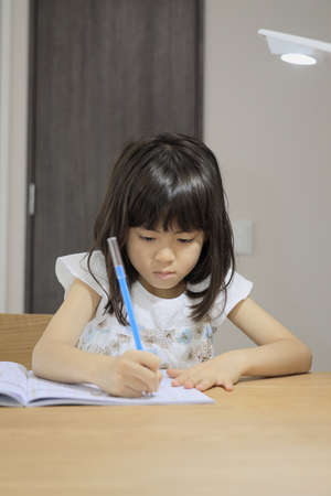 studying Japanese girl in dining room (7 years old)の写真素材