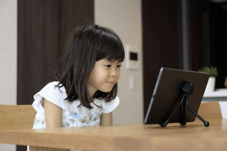 Japanese girl watching video on tablet PC (7 years old)の写真素材