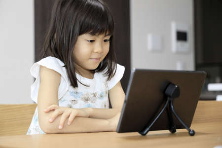 Japanese girl watching video on tablet PC (7 years old)の写真素材