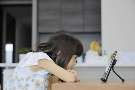 Japanese girl watching video on tablet PC (7 years old)の写真素材