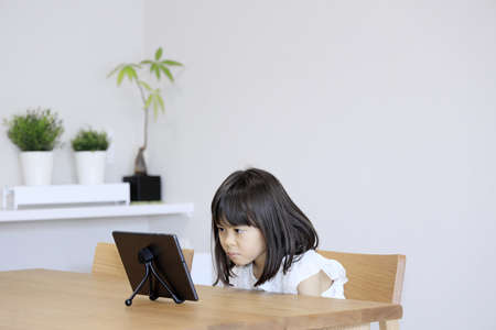 Japanese girl watching video on tablet PC (7 years old)の素材 [FY310186517767]