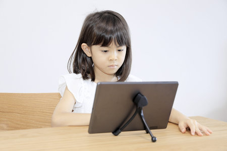 Japanese girl watching video on tablet PC (7 years old)