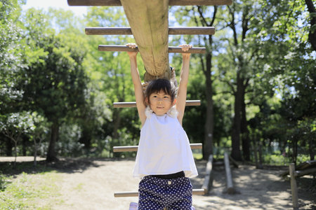 Japanese student girl playing with a monkey bars (7 years old)の写真素材