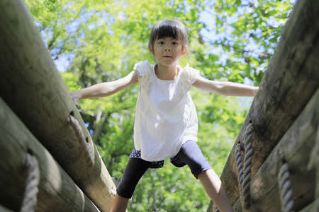 Japanese student girl playing at outdoor obstacle course (7 years old)の写真素材