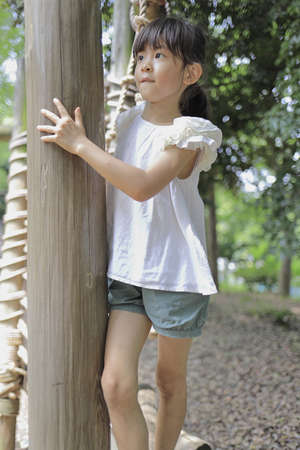 Japanese student girl playing at outdoor obstacle course (7 years old)の写真素材