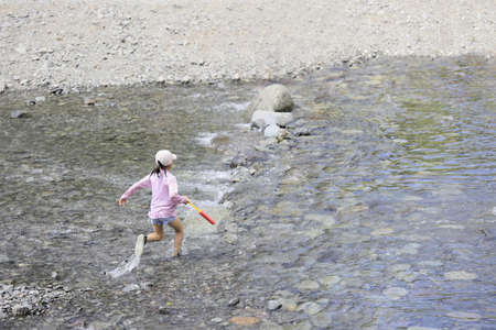 Japanese student girl playing in the river (7 years old)の写真素材