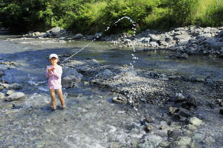 Japanese student girl playing in the river with water gun (7 years old)の写真素材