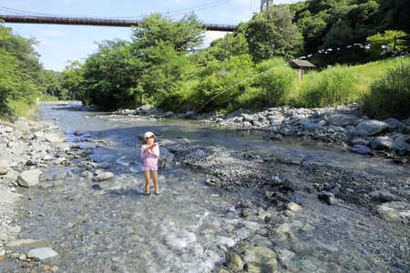 Japanese student girl playing in the river with water gun (7 years old)の写真素材