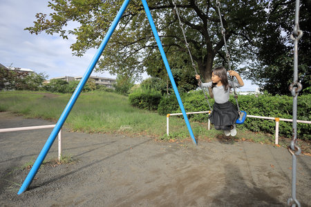 Japanese student girl on the swing (8 years old)の写真素材