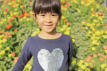 Japanese student girl in flower garden (8 years old)の写真素材