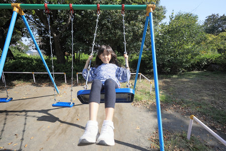 Japanese student girl on the swing (8 years old)の写真素材