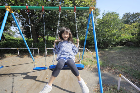Japanese student girl on the swing (8 years old)の写真素材