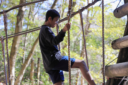 Japanese junior high school student playing at outdoor obstacle course (13 years old)の写真素材