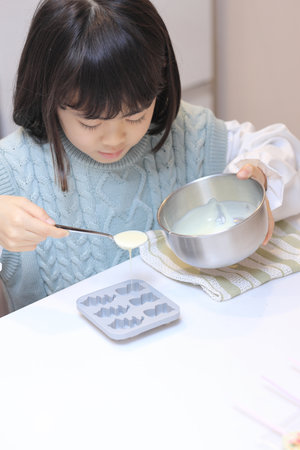 Japanese student girl cooking white chocolate (8 years old)の写真素材
