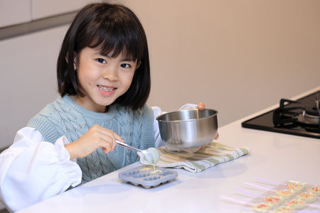 Japanese student girl cooking white chocolate (8 years old)の写真素材