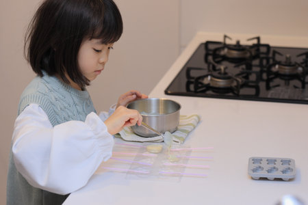 Japanese student girl cooking white chocolate (8 years old)の写真素材