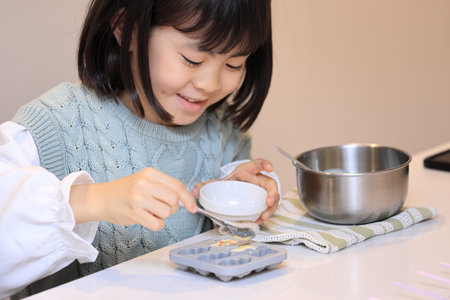 Japanese student girl cooking white chocolate (8 years old)の写真素材