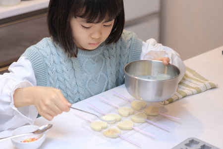 Japanese student girl cooking white chocolate (8 years old)の写真素材