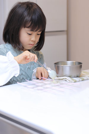 Japanese student girl cooking white chocolate (8 years old)の写真素材