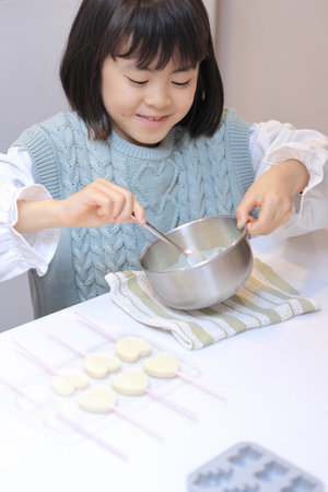 Japanese student girl cooking white chocolate (8 years old)の写真素材