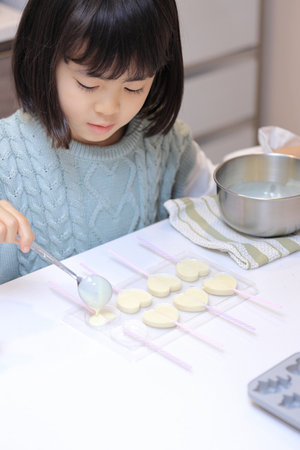 Japanese student girl cooking white chocolate (8 years old)の写真素材