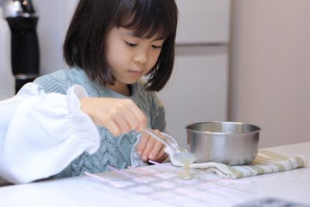 Japanese student girl cooking white chocolate (8 years old)の写真素材