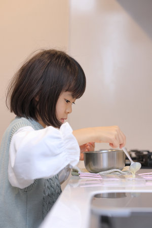 Japanese student girl cooking white chocolate (8 years old)の写真素材