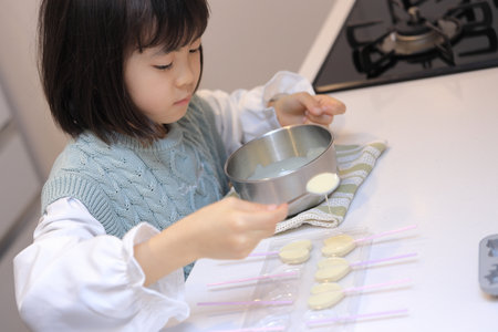 Japanese student girl cooking white chocolate (8 years old)の写真素材