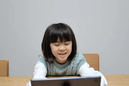 Japanese student girl watching video on tablet PC (8 years old)の写真素材