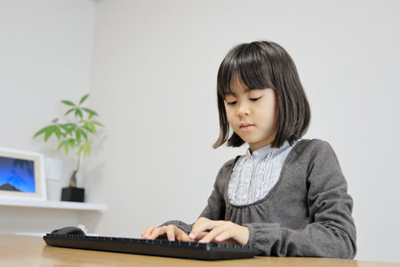 Japanese student girl typing PC keyboard (8 years old)の写真素材