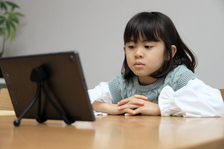 Japanese student girl watching video on tablet PC (8 years old)の写真素材