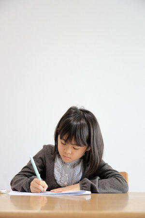 Japanese student girl studying in dining room (8 years old)の写真素材