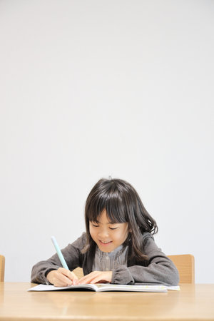 Japanese student girl studying in dining room (8 years old)の写真素材