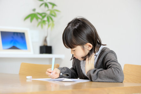 Japanese student girl studying in dining room (8 years old)の写真素材