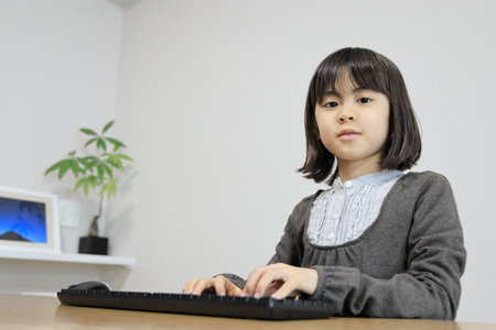 Japanese student girl typing PC keyboard (8 years old)の写真素材