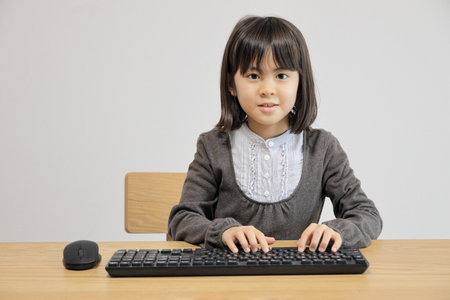 Japanese student girl typing PC keyboard (8 years old)の写真素材