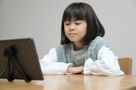 Japanese student girl watching video on tablet PC (8 years old)の写真素材
