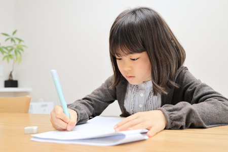 Japanese student girl studying in dining room (8 years old)の写真素材