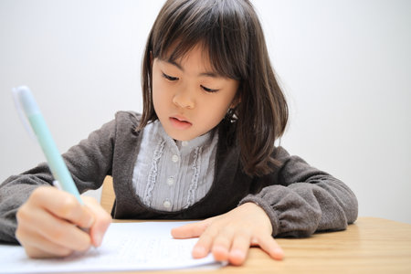 Japanese student girl studying in dining room (8 years old)の写真素材