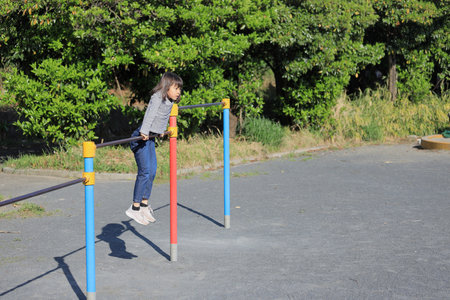 Japanese student girl playing with high bar (8 years old)の写真素材