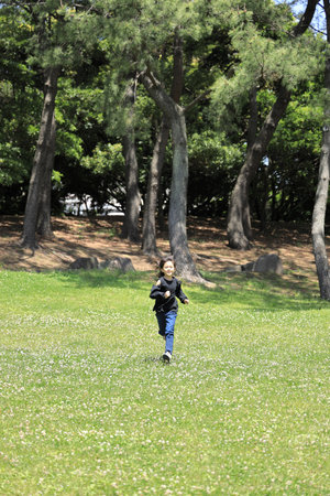 Japanese student girl running on the grass (8 years old)の写真素材