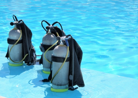 a picture of three oxygen tanks lying on the shallow part of a poolの写真素材