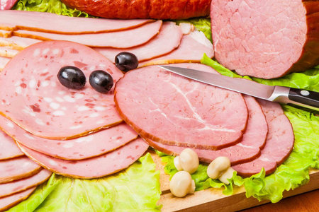 Meat delicacies (ham, sausage) on a wooden board