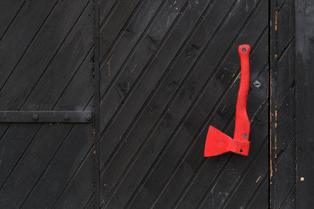 Scarlet ax on the background of a black antique wooden wall