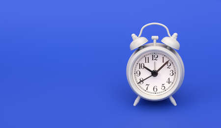 White alarm clock in old style isolated on blue backgroundの写真素材