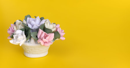 Composition with negative space. Porcelain basket with flowers isolated on yellow background
