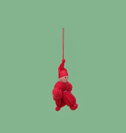 Red traditional little man made of threads isolated on a green backgroundの写真素材
