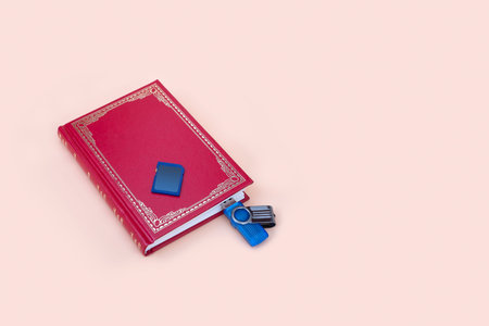 Book and memory card isolated on pink background