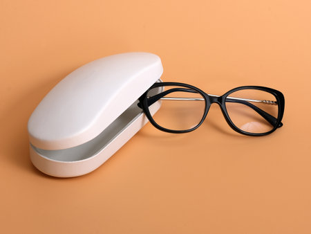 White leather spectacle case and glasses isolated on a orange backgroundの写真素材