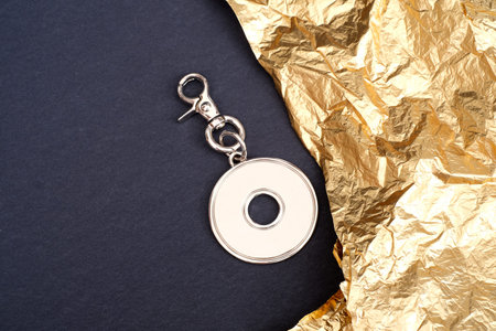 Round keychain with carabiner for bag isolated on golden background
